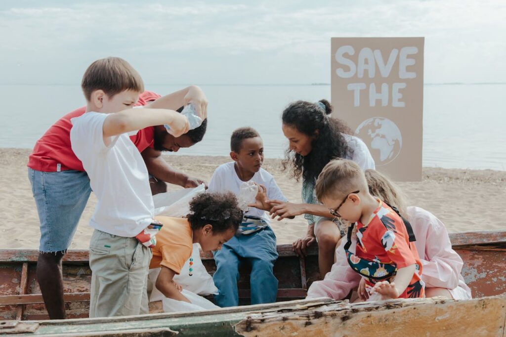 pexels photo 9037596 A group of children volunteering to clean a beach with a 'Save the Earth' sign.
